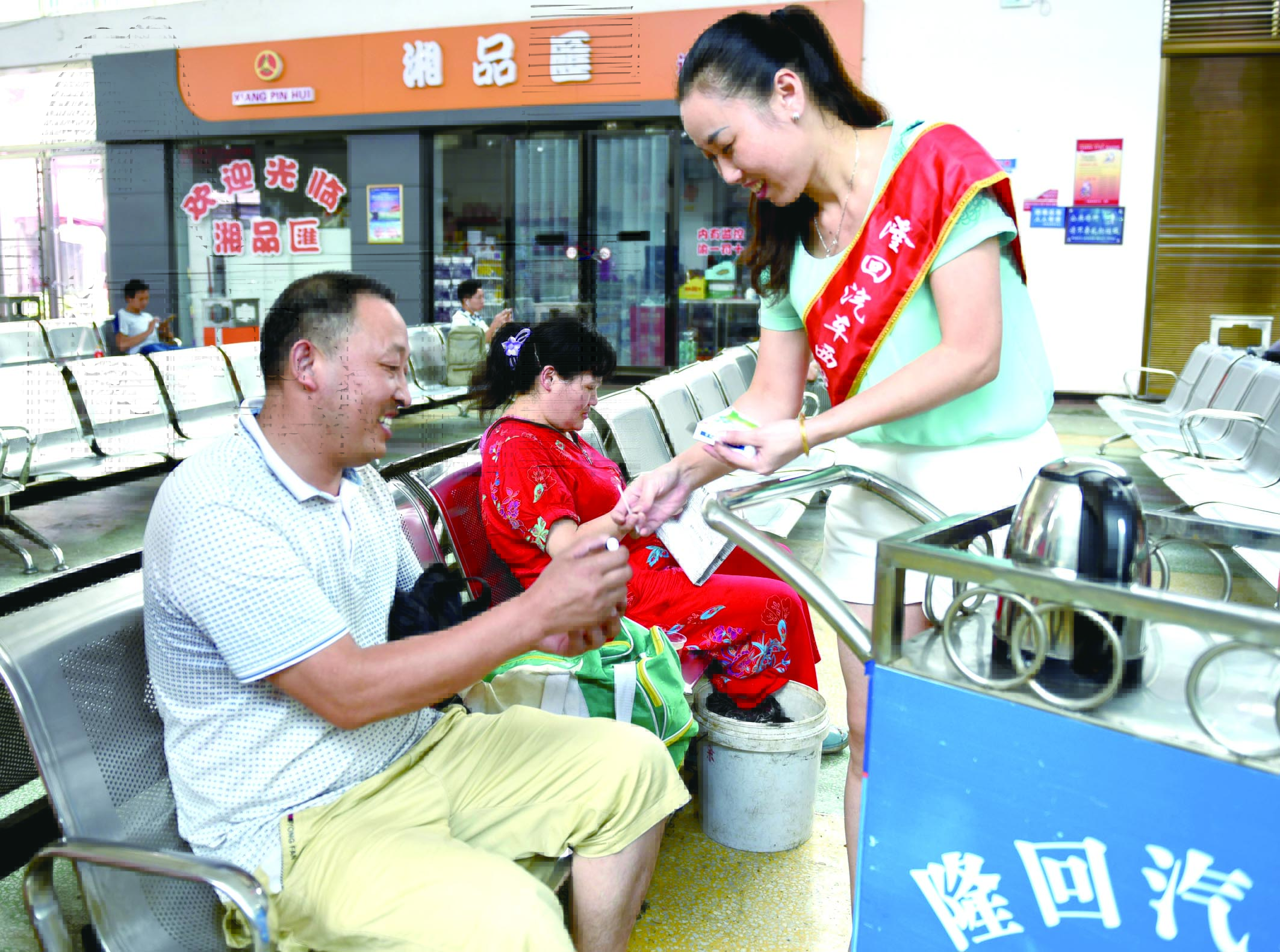 隆回分公司汽車西站工作人員正在為旅客免費贈送藿香正氣水。